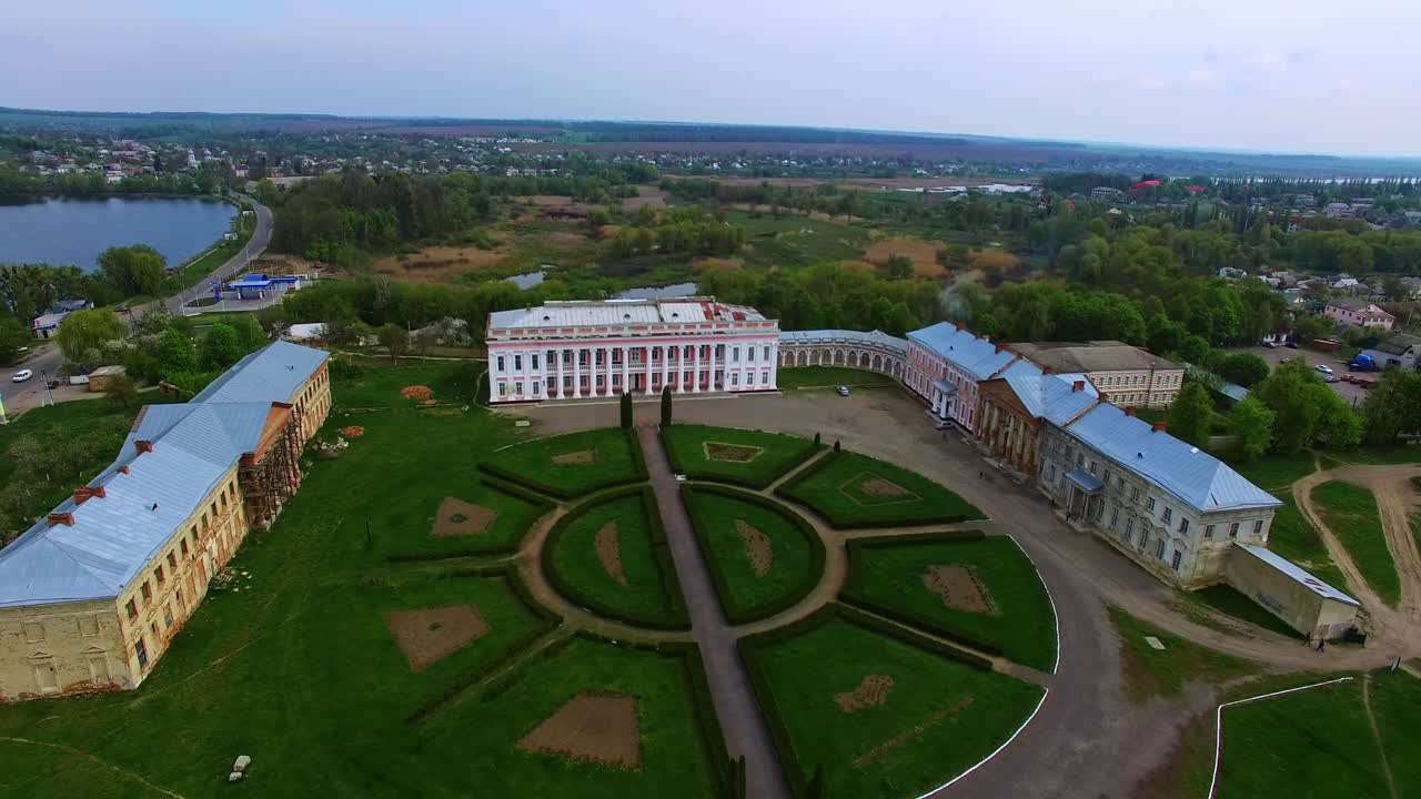 Three historical buildings in the ensemble of museum. Palaces under reconstruction with flower-bed in the middle. Cityscape at backdrop.