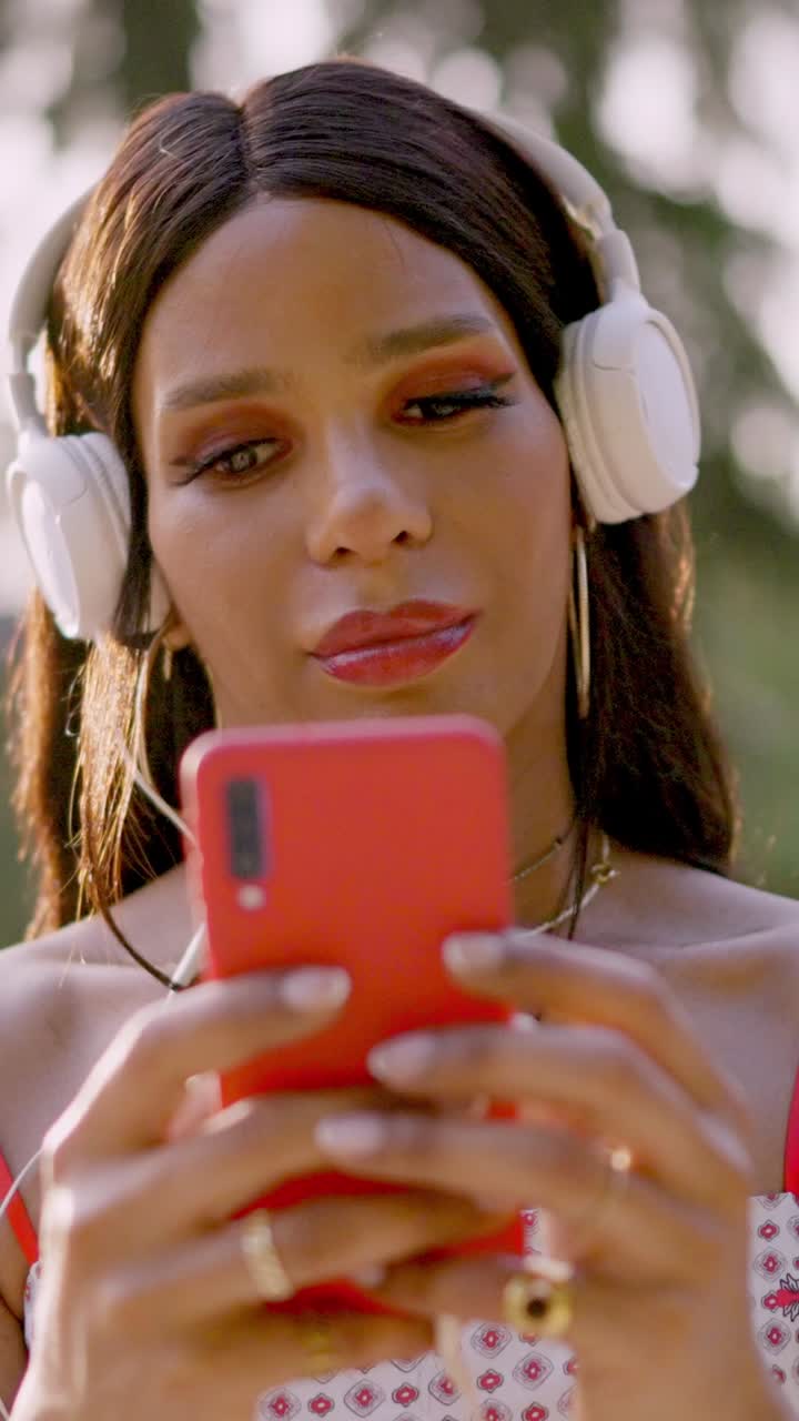 Woman enjoying music outdoors with headphones and smartphone