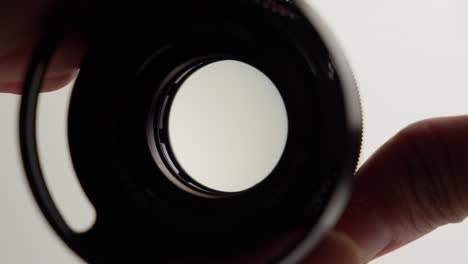 Camera-lens-aperture-opening-by-hand-with-white-background