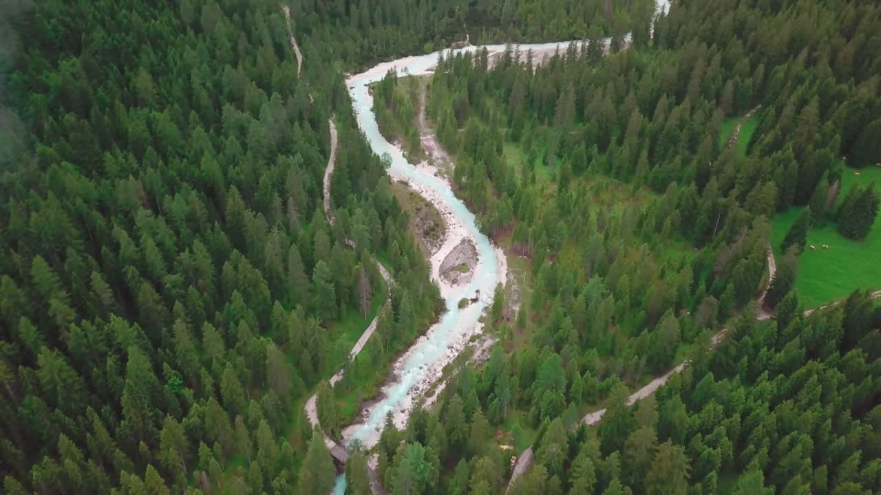 drone de alto ángulo disparado en los alpes con nubes bajas volando sobre un río rodeado por un bosque