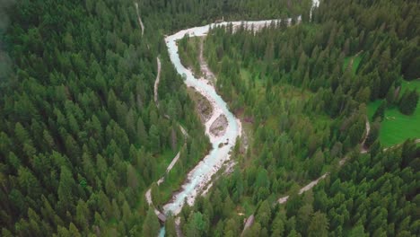 Hochwinkel-Drohne-In-Den-Alpen-Mit-Niedrigen-Wolken,-Die-über-Einem-Von-Einem-Wald-Umgebenen-Fluss-Fliegen