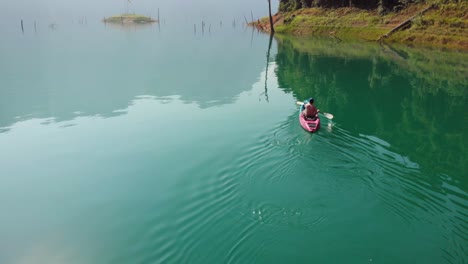 Mann,-Der-Auf-Einem-Ruhigen-Cheow-Lan-See-Im-Khao-Sok-Nationalpark-Unter-Dem-Hellen-Sonnigen-Tag-In-Thailand-Kajak-Fährt