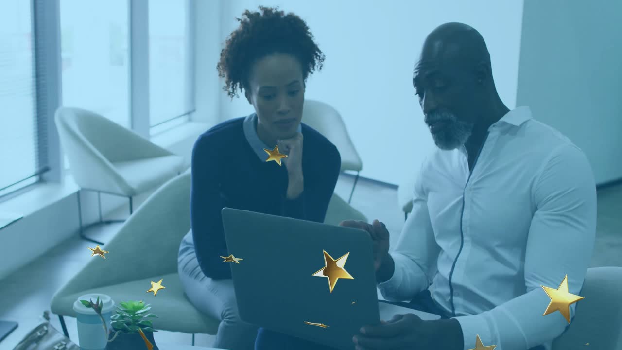 Une équipe tapant sur un ordinateur portable et collaborant dans un espace de détente professionnel, créant des animations en forme d’étoiles qui dérivent puis s’estompent