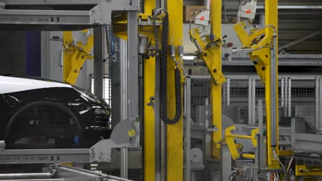 black car on assembly line with robotic arms in modern automotive factory, industrial setting