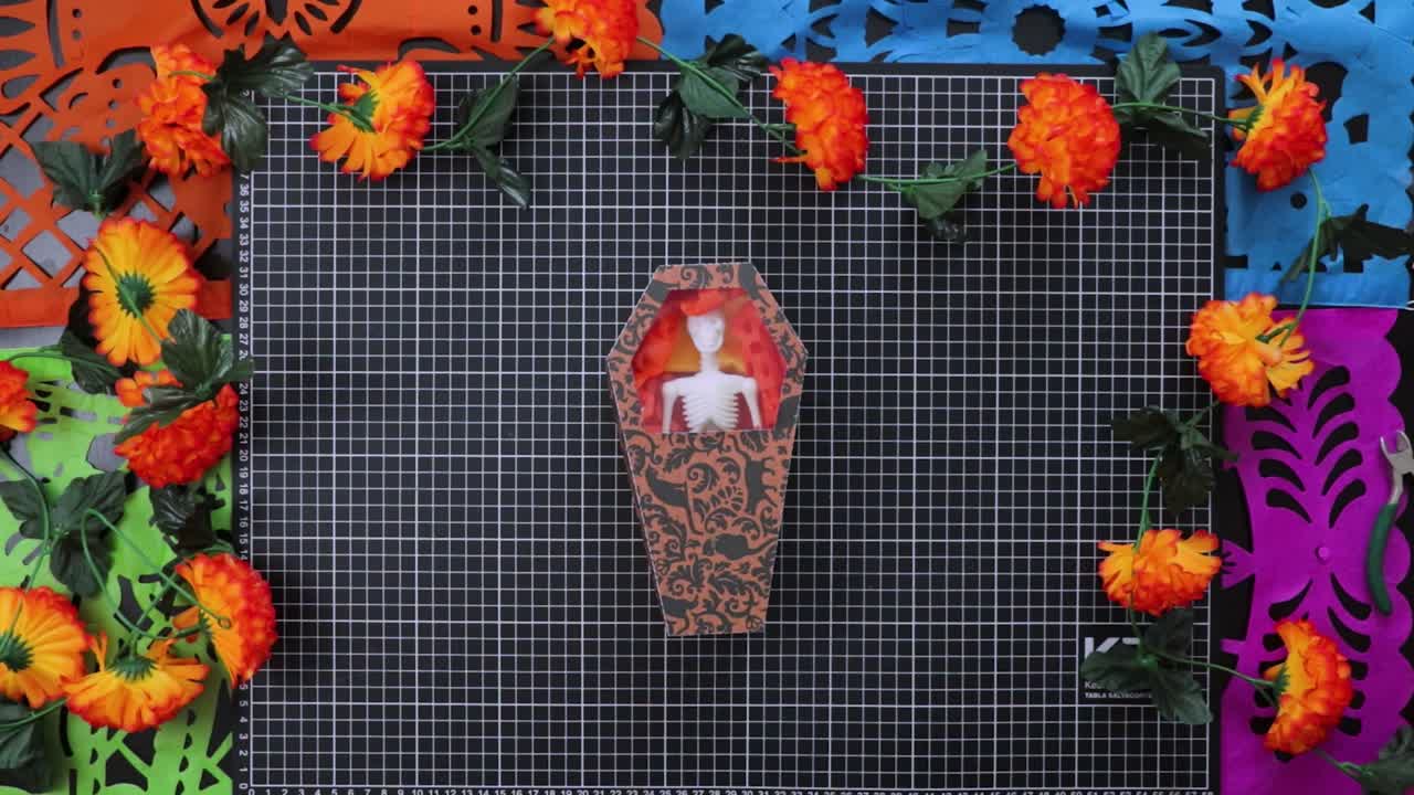 POV of person holding small cardboard box with skeleton inside. Traditional Mexican decoration