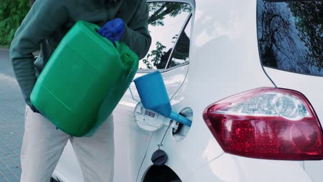 a man pouring gasoline into an empty fuel tank from a plastic red  gas can. filling  the car from the canister into the neck of the fuel tank.