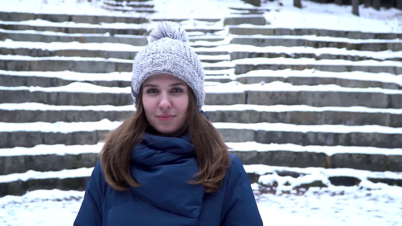 mujer con sombrero y abrigo de invierno en un parque nevado