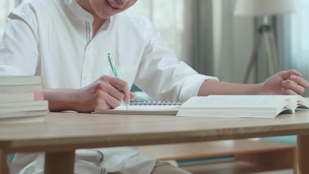 Close Up Of A Happy Asian Man Student Writing In Notebook On The Table While Studying At Home