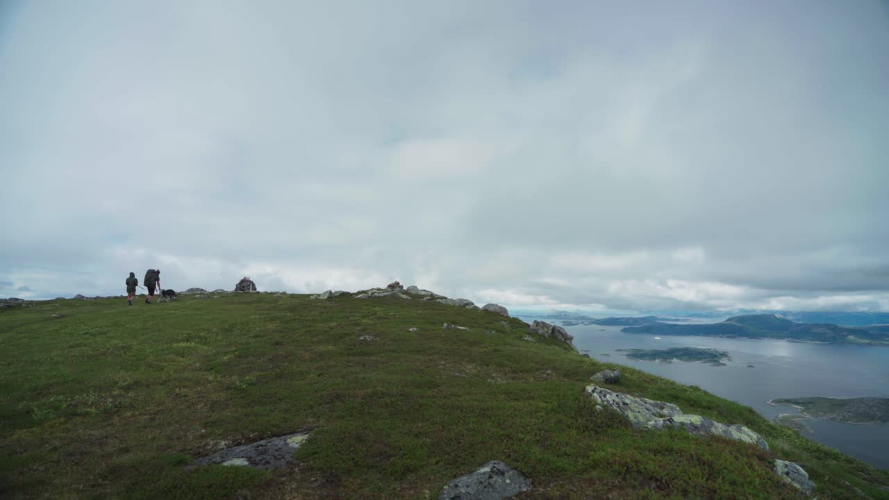 노르웨이의 흐린 루뢰위펠렛 산 정상에 개를 데리고 있는 등산객들
