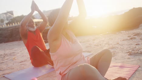 una feliz pareja de ancianos afroamericanos haciendo yoga, meditando en la playa, cámara lenta