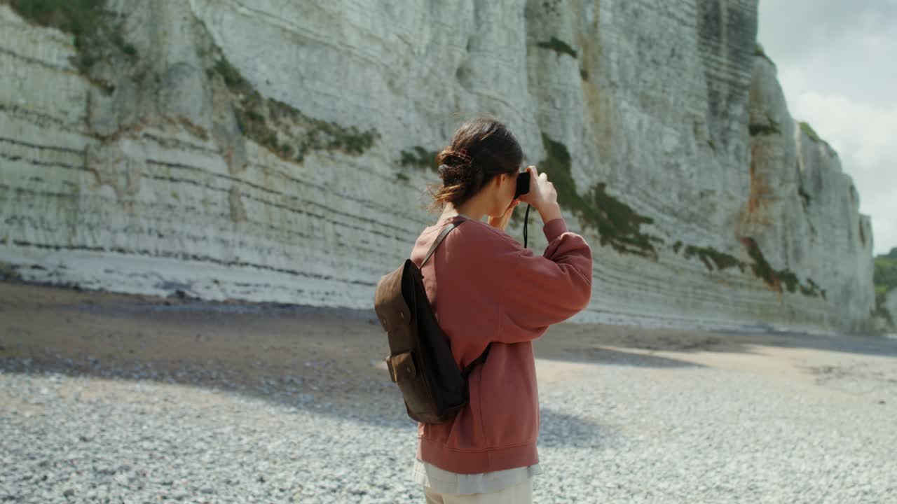 mujer tomando fotos en la playa en una zona costera