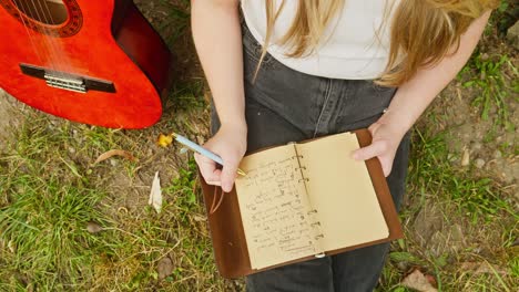 young woman composer musician writes chords lyrics song book down shot