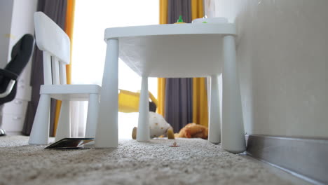 little toddler boy crawls under the white desk. caucasian child playing at home.