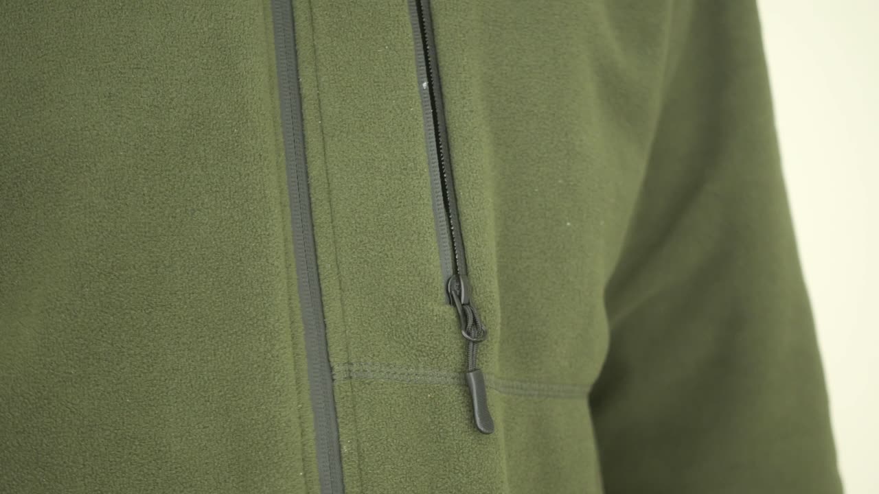 Person zipping up a green fleece jacket