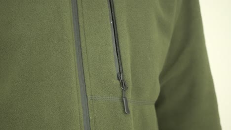 person zipping up a green fleece jacket