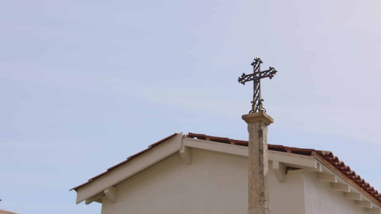 cruz y construcción exterior de una iglesia contra el cielo dramático