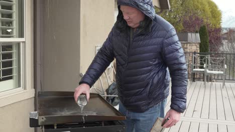 man pour water on a hot flat top griddle after cooking to clean it - steam in slow motion