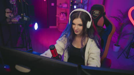 curious girl wearing white headphones playing video game with red condenser microphone close by in neon lit studio, focused expression, colorful gaming chair and drum kit backdrop, ambient lighting