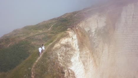 personas caminando por acantilados costeros con niebla