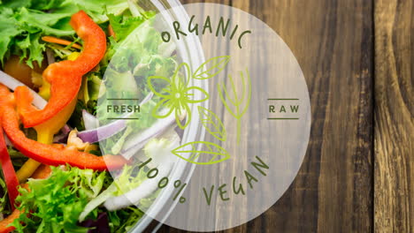 animation of organic 100 percent vegan text in green, over bowl of fresh salad on wooden boards