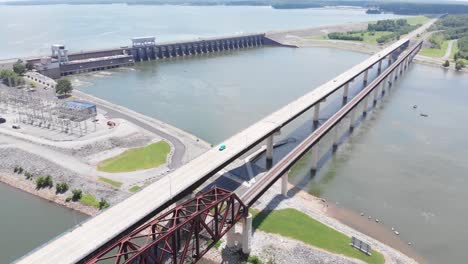 railroad and vehicular bridge over water with dam in background, kentucky, backward aerial