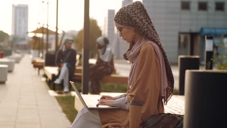 Woman-Using-Laptop-on-Bench-Outdoors