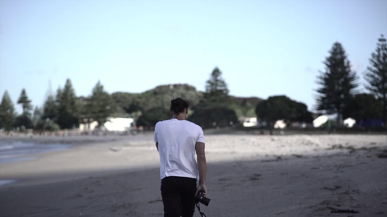 A man walking on the beach with a camera
