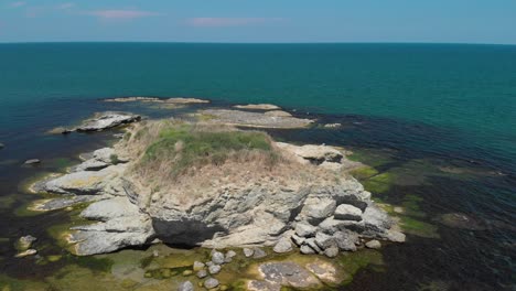 Aerial-arc-shot-of-big-cliffs-in-the-sea-with-vegetation-and-birds-1