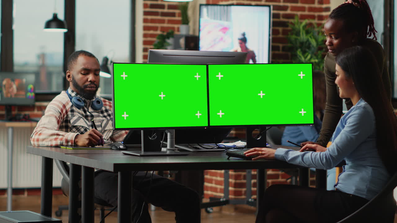 Diverse team of female employees analyzing computers with greenscreen