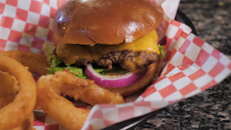 cheeseburger and beer battered onion rings served on red checkered paper, slider slow motion close up hd