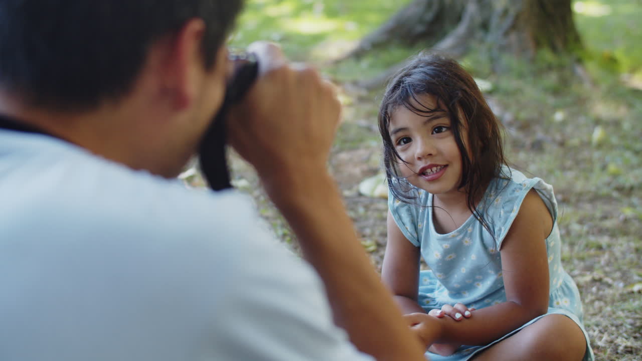 niña asiática feliz sentada en el suelo mientras el padre toma una foto