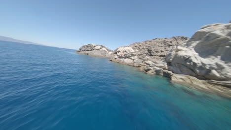 fpv aerial drone flying fast above turquoise sea water in cap de creus, spain