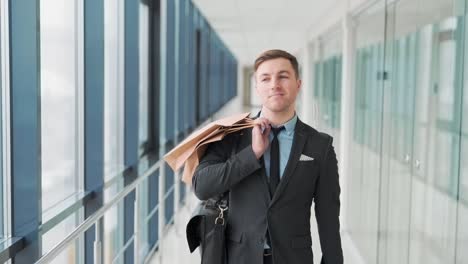 Pretty-smiling-man-walks-down-the-hall-of-shopping-mall-after-shopping