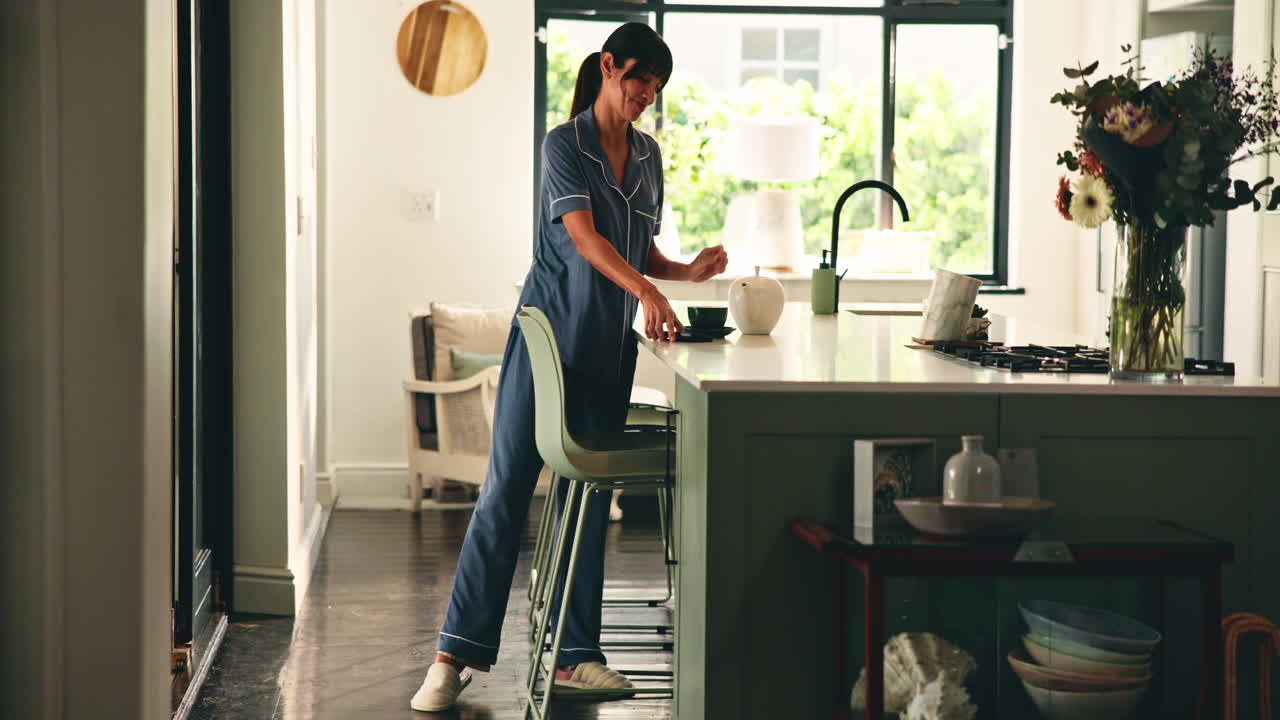 Donna in abiti che parla al telefono in cucina