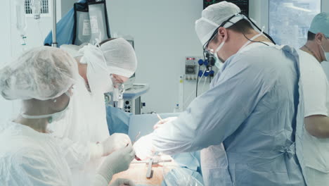 scrub nurse gives sterile tool to doctor. experienced surgical team performs surgery on heart creating new vessels to divert blood supply in clinic