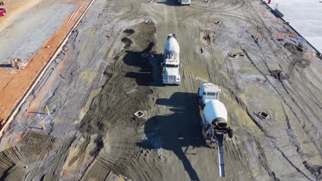 una línea masiva de camiones de concreto se cruza en un sitio de construcción