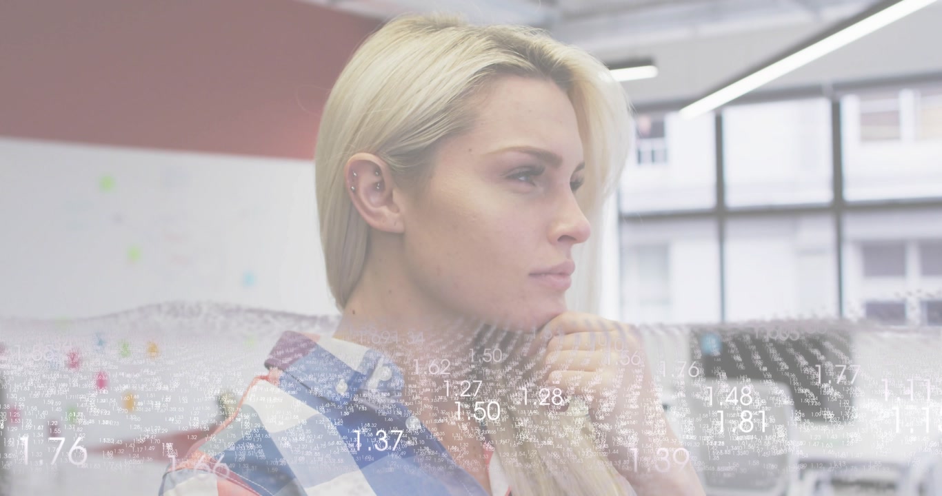 With floating numerical data overlay appearing, woman standing in office analyzing finance figures