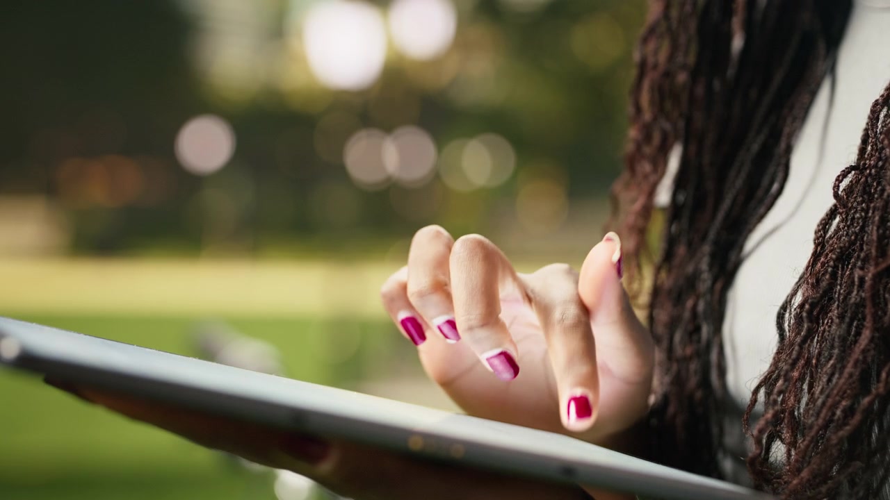 Primo piano di un corriere che usa le dita per navigare su un tablet touchscreen all'aperto.