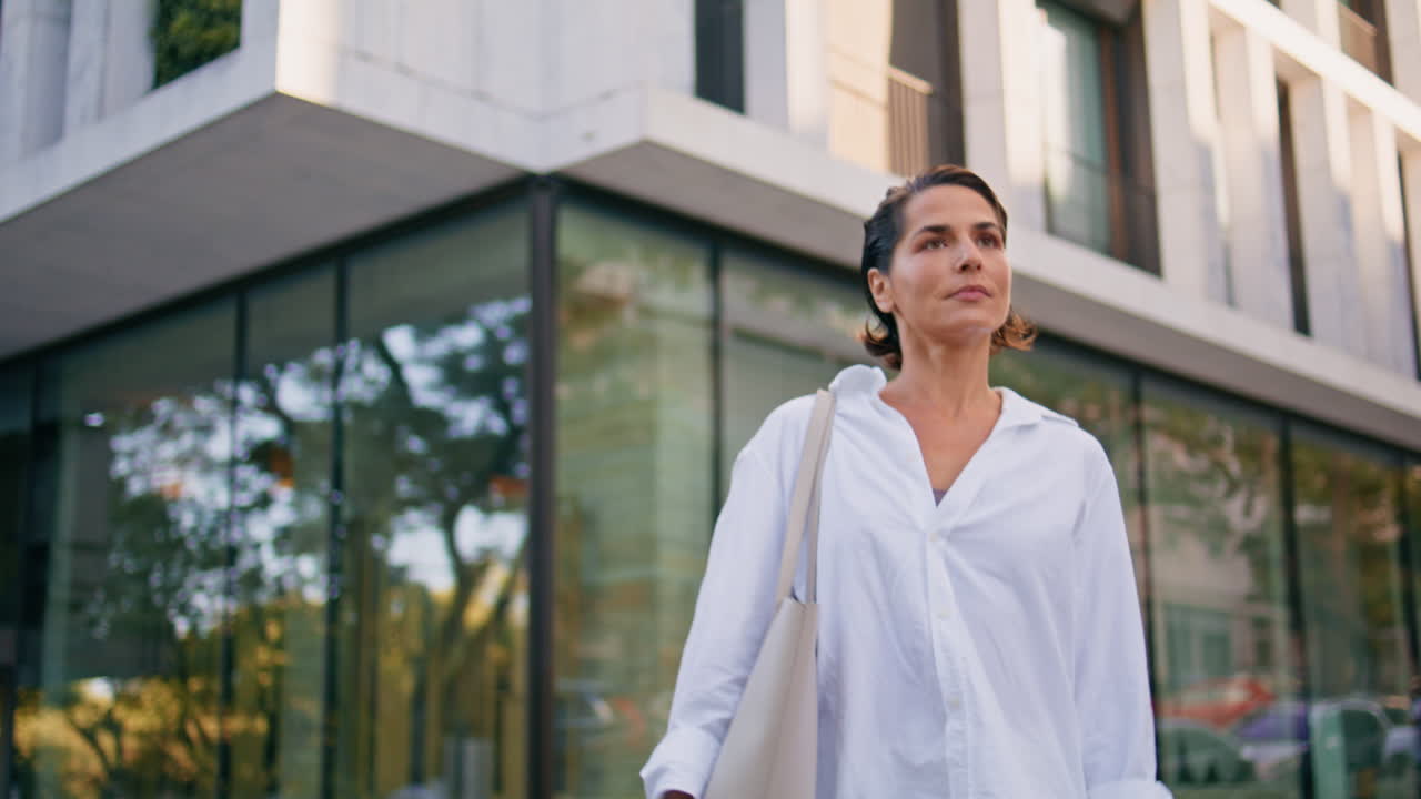 mujer segura caminando por la calle del distrito de negocios de primer plano. agente maduro paseando
