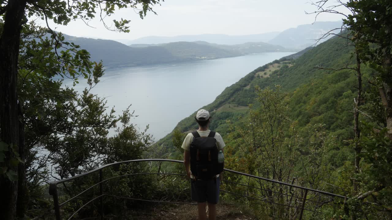 Hiker enjoying a panoramic view of a lake and mountains