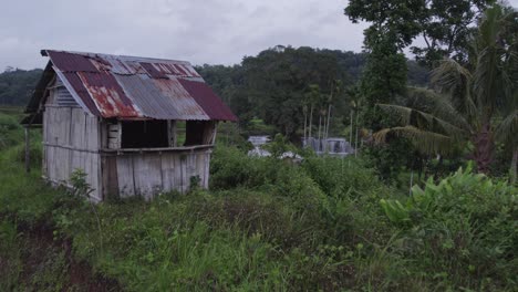 Reveal-shot-of-small-hut-next-to-the-Waikelo-Sawah-Waterfall-at-Sumba-island,-aerial