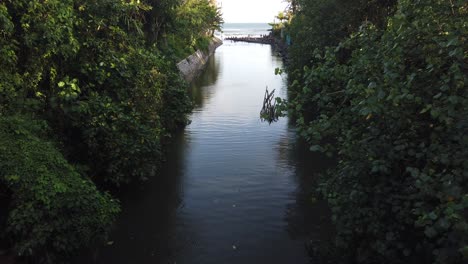 River-Mouth-in-Between-Lush-Green-Vegetation-Opens-up-to-Blue-Water-Beach-Shore-and-Clear-Sky-in-Bali,-Indonesia,-Pantai-Saba-Blahbatuh,-Gianyar,-60-Fps