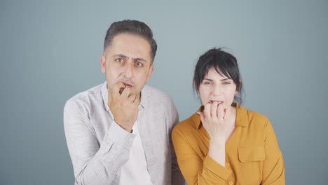 una pareja mordiendo uñas en el estrés contra la cámara.