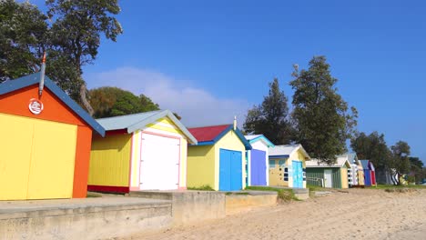 vibrant beach huts line the sandy shore under clear blue skies, creating a lively and picturesque coastal scene