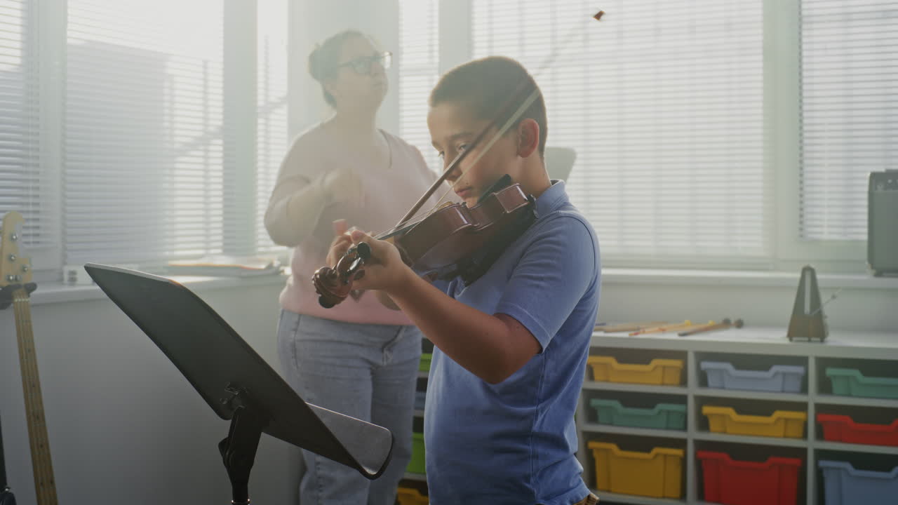 Talented Boy Playing Violin From Notes During Music Lesson Teacher Supporting Young Musician