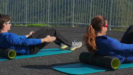 couple performing outdoor foam rolling exercises