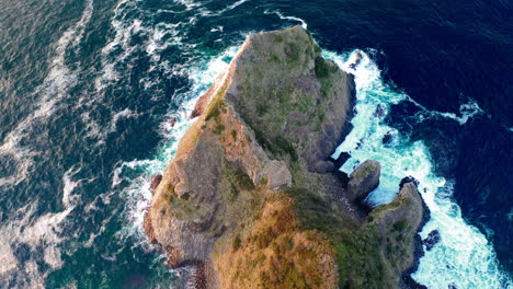 cinematic drone shot tilting downwards to a large rock on the coastline at kyushu japan