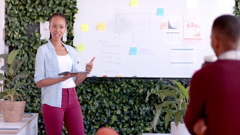 African-american-casual-businesswoman-making-presentation-at-whiteboard-in-office,-slow-motion