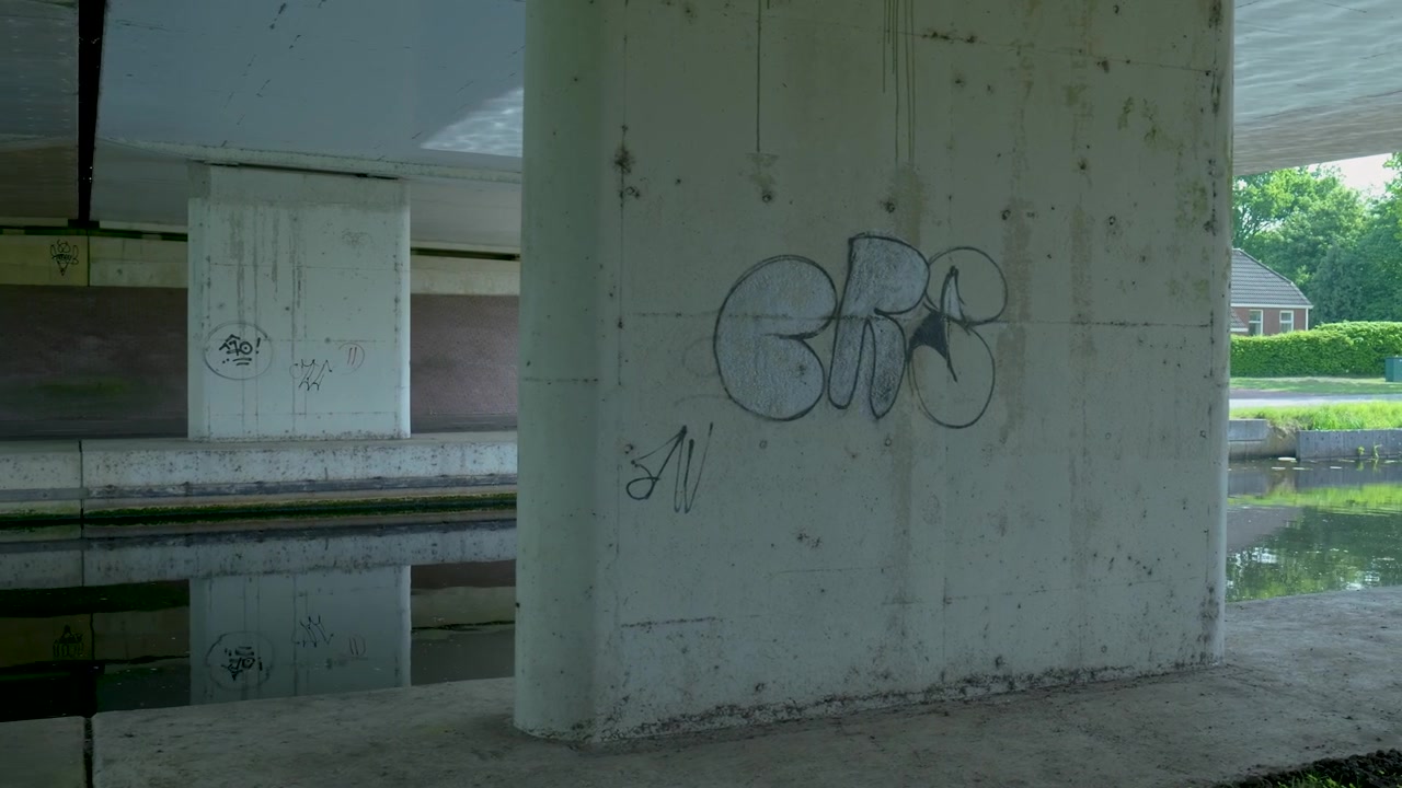 Graffiti su pilastri di un ponte in cemento sopra un canale