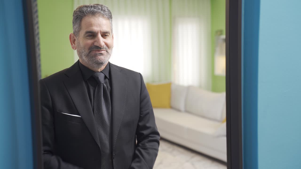 Uomo d'affari maturo allegro e piacevole che si guarda allo specchio e si sente felice.